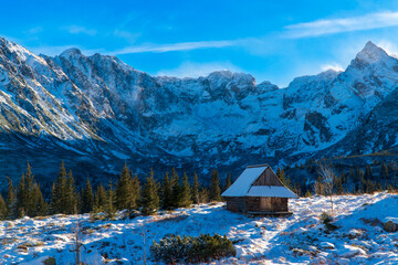 Beautiful, panoramic view to the snow covered mountains in tatras national park with house , zakopane poland. during a cold winter morning Mountain wooden cottage by the slopes.