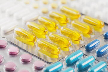 A bunch of medical pills in yellow and other colors. Tablets in plastic packaging.