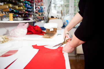 Tailor working with cloth at table in atelier.