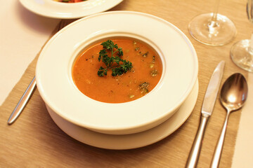 Lentil and broccoli puree soup in white plate served on table in restaurant. 