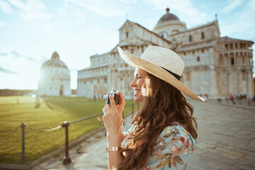 smiling modern woman in floral dress with retro camera and hat
