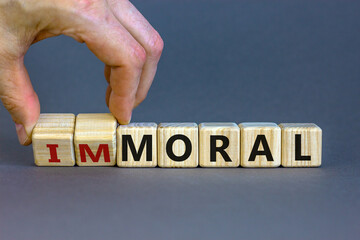 Moral or immoral symbol. Hand turns cubes and changes the word 'immoral' to 'moral'. Beautiful grey...