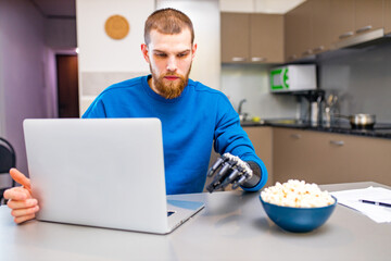 young man watching a movie in laptop and eating pop corn at home