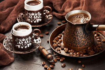Hot coffee in Turkish copper  pot, traditional mugs  and coffee beens