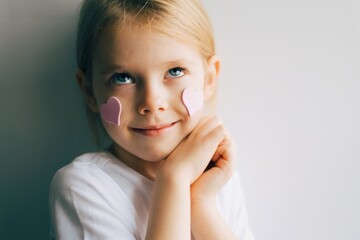 Cute blue-eyed little girl holding pink heart for valentines day. Lovely smiling child with heart. Hipster. Love. - 404924698