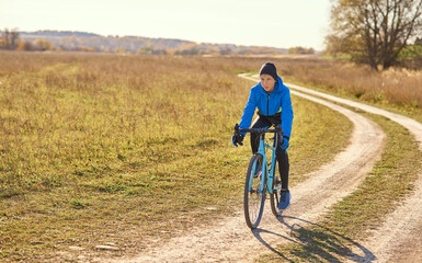 A young athlete on a sports bike rides cross-country in sunny weather.