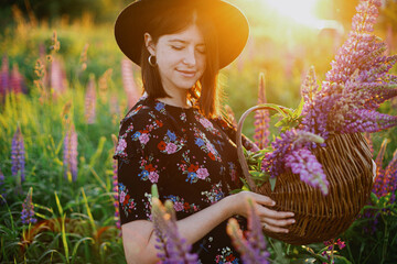 Portrait of woman in lupine field in countryside meadow at sunset. Tranquil atmospheric moment