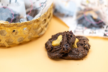 Dark Chocolate Cookies with raisin inside it on the light orange colour background.