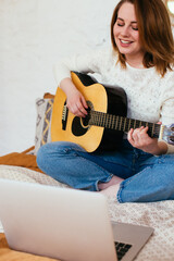 Female vlogger filming herself playing a guitar. Guitar lessons online