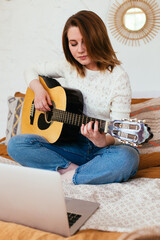 Female vlogger filming herself playing a guitar. Guitar lessons online
