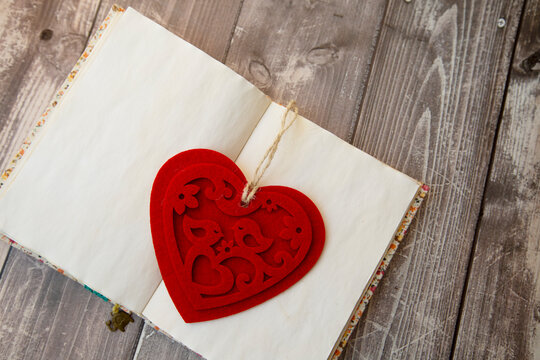 a red heart-shaped photo frame lies on an open notebook, top view. valentines day