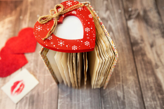 red photo frame in the shape of a heart lies on the pages of a vintage notebook
