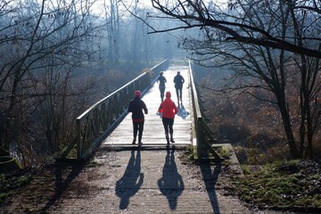 Budapest, Hungary - January 1, 2021: New year morning runners on a wooden bridge on a foggy winter morning in Budapest suburb, Hungary 