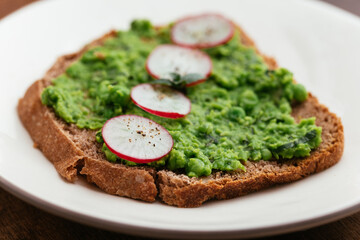 Slice of bread with a home made minty pea spread with radishes