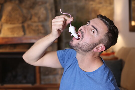 Man pretending to eat plastic mouse 