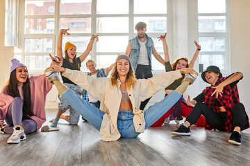 group of young dancers performing a common choreography in modern dance studio, wearing trendy...