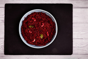 Beetroot curry made from grated beetroot with coconut milk, grated coconut and cashews. Indian cuisine meal in plate placed on black slate. Top view.