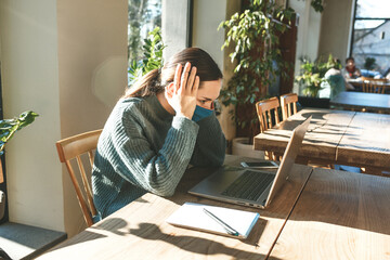 Girl student or freelancer uses a laptop. She thinks or is disturbed by noise or upset.