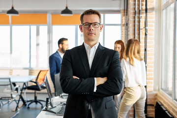 businessman in modern office after meeting,stand with arms folded, looking at camera seriously