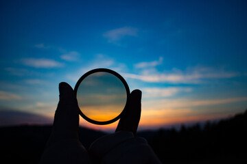 Hand holding filter lens camera, sunset, mountain, landscape