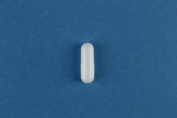 One medical pill on a blue background