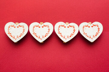 Close-up of four wooden hearts. Red background.