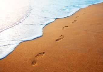 footprints on  tropical beach and beautiful  wave