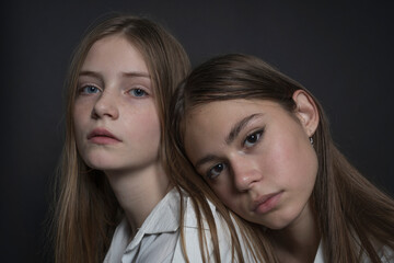 Portrait of two beautiful young girls on a black background