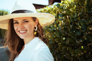 Portrait of happy modern female in white shirt with hat