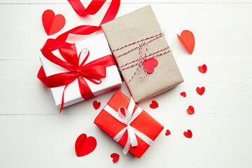 Valentines day gift boxes and red paper hearts on white wooden background