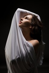 Woman wrapped in cloth outstretching arms in studio