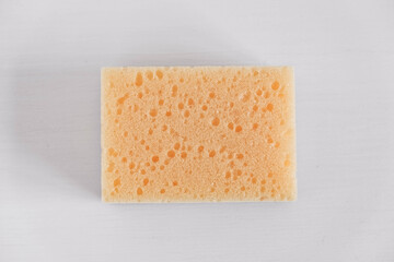 Yellow porous sponge on a white background. Top view. Copy, empty space for text
