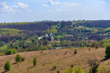Fototapeta na wymiar Spring landscape with forest, meadow, hills, lake, small village and orthodox church in Central Ukraine
