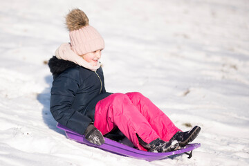 Little girl sliding with bob and falling in the snow.