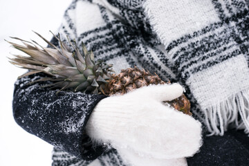 Girl in mittens holds pineapple in winter