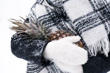 Girl in mittens holds pineapple in winter