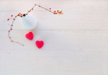 Holiday background for Valentine's day. Two sweet red hearts and abstract branches barberry on white wooden background. Copy space, selective focus. Top view