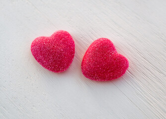 Two sweet red candy heart shape on white wooden background, close-up. Valentine's day, romantic concept. Selective focus