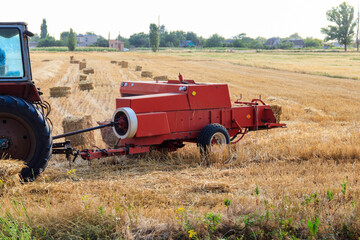 Rectangular baler discharges a straw bale in a field during the harvesting process