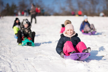 Fototapeta na wymiar Little girl sliding with bob and falling in the snow.