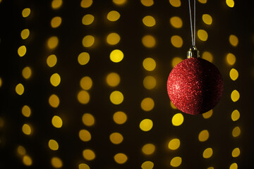 Red Christmas ball on a background of garlands. Christmas and new year concept. Bokeh garlands.