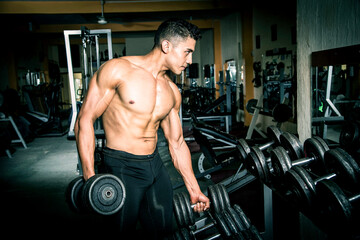Fototapeta na wymiar Young man exercising in dark and old gym