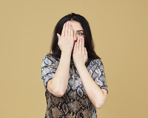 the brunette covered her face with her hands. photo shoot in the studio on a yellow background