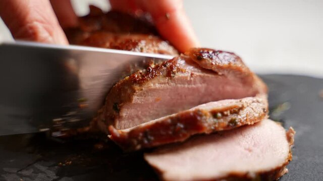 Woman cuts juicy duck fillet with knife.