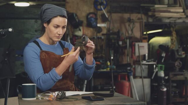 Female blacksmith wearing apron working on design in forge - shot in slow motion