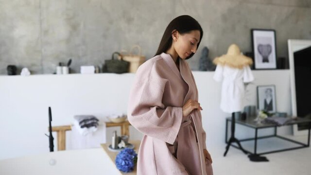 A girl in a bath and takes off her bathrobe