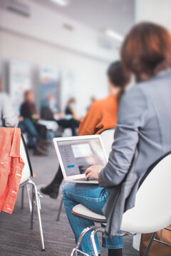 Woman Sitting At Conference Meeting Taking Notes On Laptop