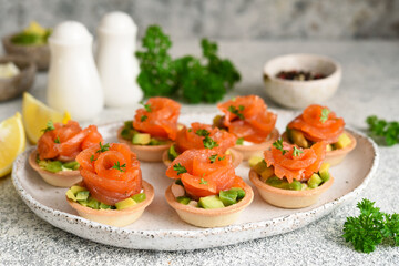 Tartlets with cream cheese, avocado and salmon. Salmon appetizer on the kitchen table.