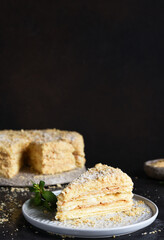 Slice of Napoleon cake with custard on a dark concrete background. Horizontal focus.