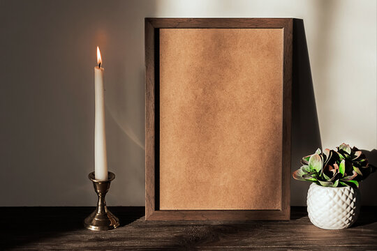 Retro interior with photo frame mockup on a wooden brown shelf, a plant in a white pot and a burning candle. Space for text, copy space.